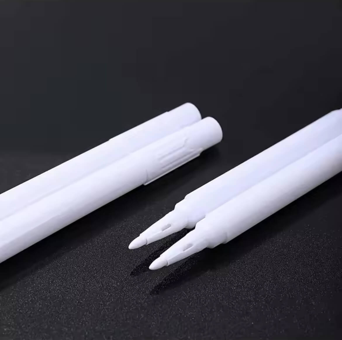 4 Kreidestifte ,zwei von denen sind offen, auf einem schwarzen Untergrund