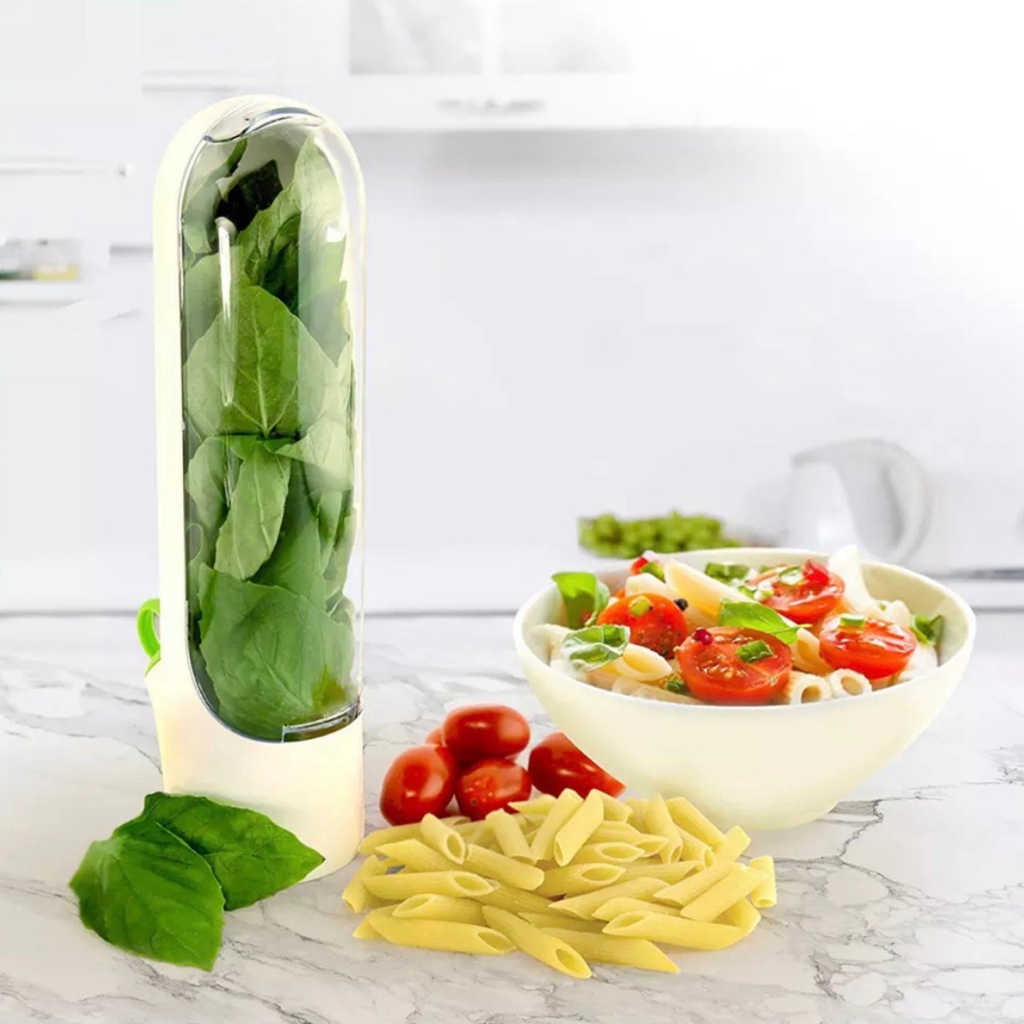 Kräuter-Frischhaltebecher mit frischen Basilikumblättern auf einer Küchenarbeitsplatte. Im Hintergrund eine Schüssel mit frischem Nudelsalat, garniert mit Basilikum, Kirschtomaten und Mozzarella. Dieser innovative Becher sorgt für frisches und griffbereites Basilikum, ideal für die Zubereitung gesunder und schmackhafter Gerichte.