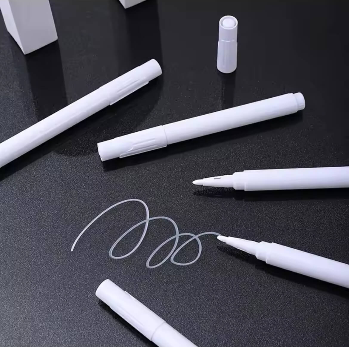 Mehrere kreidemarker,ein davon offen,auf einem schwarzen Untergrund arrangiert-ideal für glatte Oberflächen wie Glass, Tafeln oder Etiketten.