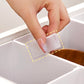 Nahaufnahme einer Hand, die eine kleine, weiße Verbindungsstück an einer stapelbaren Aufbewahrungsbox mit Griff befestigt, um zwei Boxen nebeneinander zu sichern. Die Verbindungsteile verhindern das Rutschen und sorgen für eine stabile, einheitliche Struktur der Boxen. Dieses Detail zeigt die durchdachte Konstruktion der Aufbewahrungsboxen, die für Ordnung und Systematisierung zu Hause sorgen.