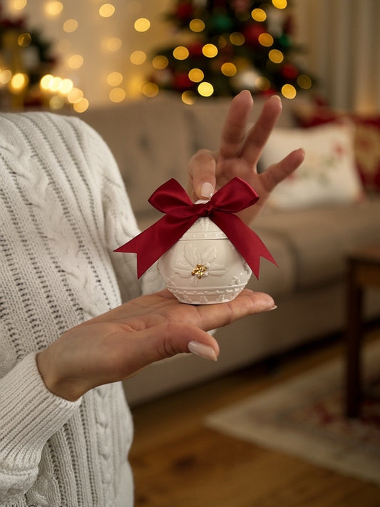 Frau hält handgefertigten Weihnachtskerzenhalter in Kugelform mit roter Schleife – festliche Deko aus der Schweiz