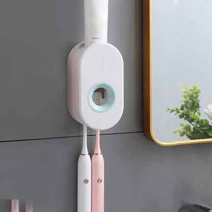 Ein weißer Zahnpastaspender mit runder Form, an einer Wand montiert, mit zwei daran hängenden elektrischen Zahnbürsten, eine in Weiß und eine in Rosa, in einem modernen Badezimmer.