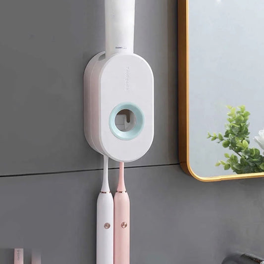 Ein weißer Zahnpastaspender mit runder Form, an einer Wand montiert, mit zwei daran hängenden elektrischen Zahnbürsten, eine in Weiß und eine in Rosa, in einem modernen Badezimmer.