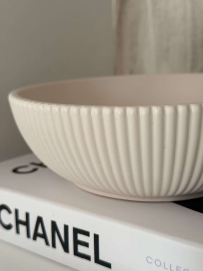 Cremeweiße, handgefertigte Schale mit gerippter Struktur, dekorativ auf einem Chanel-Buch präsentiert