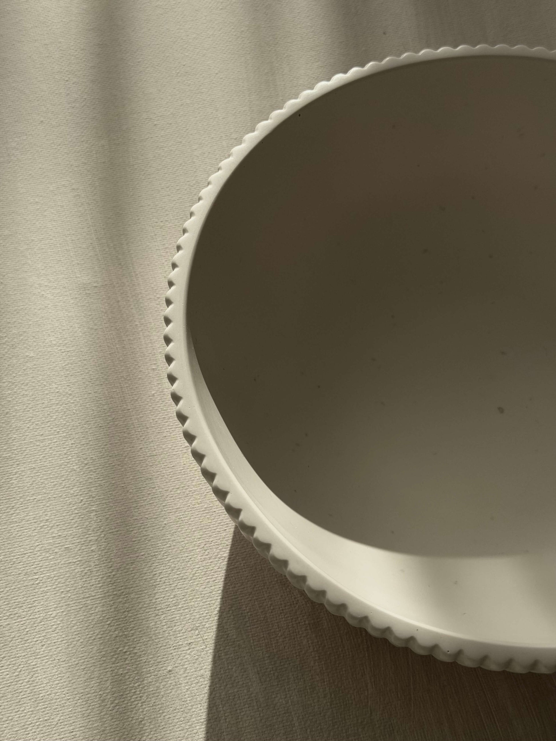 Oberansicht einer cremeweißen, handgefertigten Schale mit feiner Rillenstruktur, fotografiert im natürlichen Licht