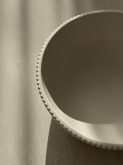 Oberansicht einer cremeweißen, handgefertigten Schale mit feiner Rillenstruktur, fotografiert im natürlichen Licht