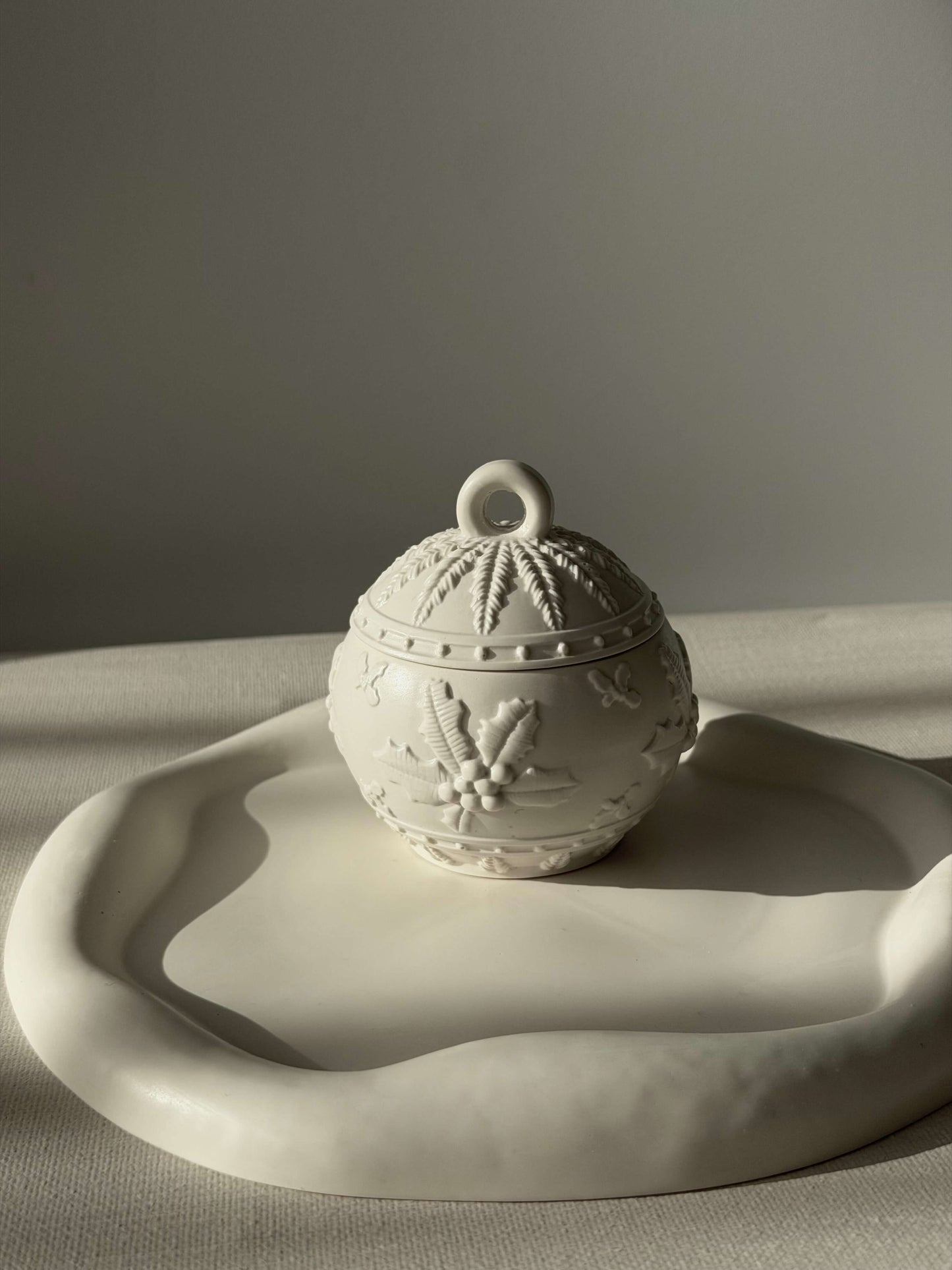 Handgefertigter Weihnachtskugel-Kerzenhalter in Weiß, dekorativ auf einem organisch geformten Tablett im warmen natürlichen Licht präsentiert