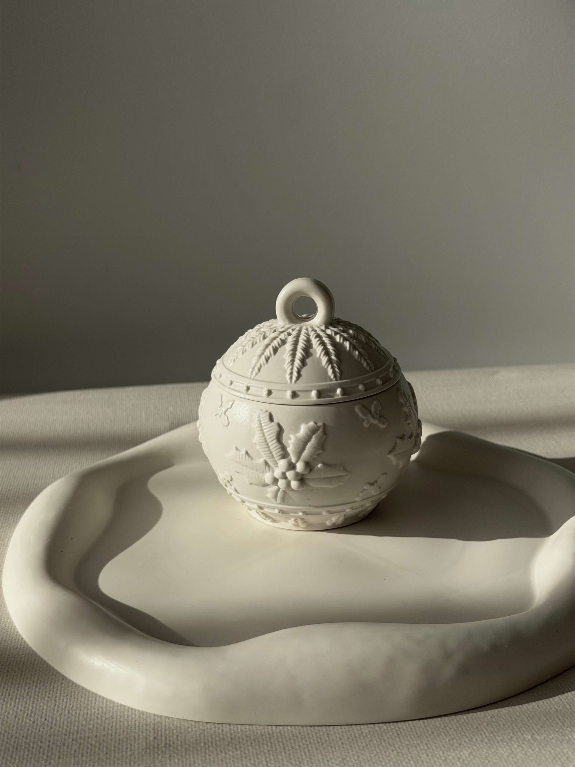 Handgefertigter Weihnachtskugel-Kerzenhalter in Weiß, dekorativ auf einem organisch geformten Tablett im warmen natürlichen Licht präsentiert