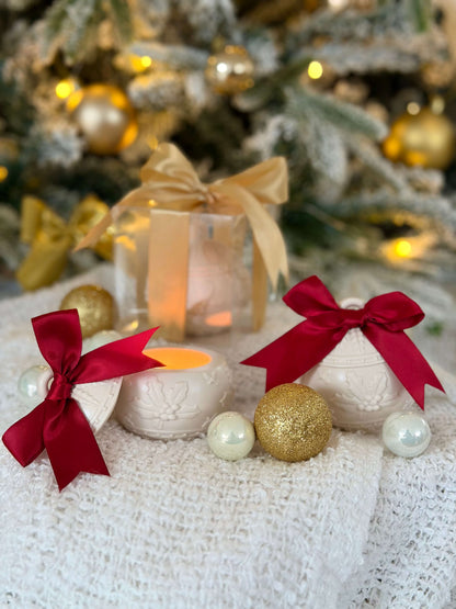 Handgefertigte Weihnachtskugel-Kerzenhalter mit roter Schleife und Geschenkbox, dekorativ mit goldenen Weihnachtskugeln vor einem beleuchteten Weihnachtsbaum arrangiert