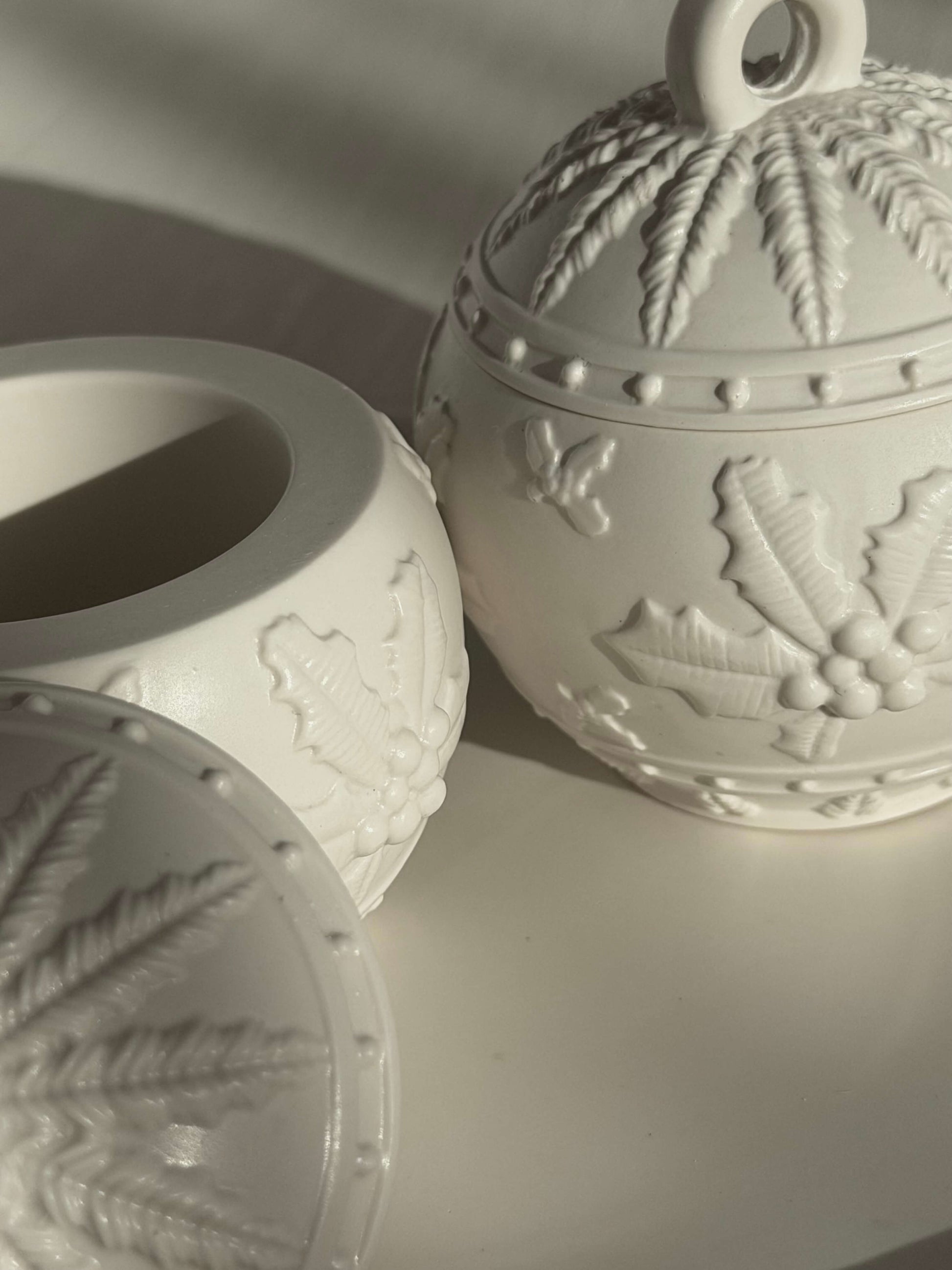 Geöffneter handgefertigter Weihnachtskugel-Kerzenhalter mit detailliertem Winterrelief, bestehend aus Unterteil und Deckel, im natürlichen Licht fotografiert