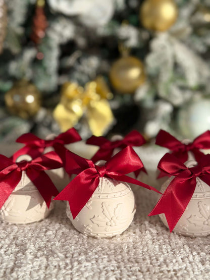 Handgefertigte Weihnachtskugel-Kerzenhalter mit roten Schleifen, dekorativ vor einem festlich geschmückten Weihnachtsbaum arrangiert