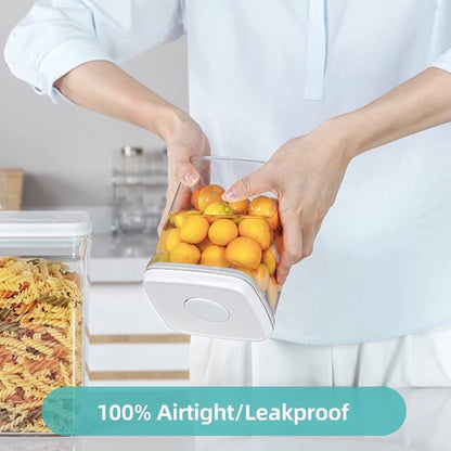 Eine Person in weißer Küchenkleidung hält eine transparente, rechteckige Vorratsdose mit einem einfachen, weißen Pop-up-Verschlussmechanismus, gefüllt mit frischen, orangefarbenen Kumquats. Im Hintergrund ist eine moderne Küchenumgebung zu erkennen. Über dem Bild steht ‚100% Airtight/Leakproof‘, was die Dichtheit und Auslaufsicherheit der Dose hervorhebt.