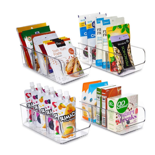 Vier transparente iDesign Acryl-Aufbewahrungsbehälter, gefüllt mit verschiedenartigen Lebensmittelverpackungen. Im oberen Behälter sind Gewürzpackungen wie Tom Yum Paste und Frühstücksmix, im unteren sind farbenfrohe Saftbeutel von Sumo und Snackpackungen angeordnet. Die klare Struktur der Organizer sorgt für eine ansprechende und übersichtliche Präsentation.