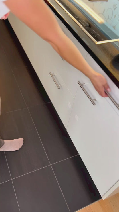 Das Video demonstriert die Benutzung eines hölzernen Folienspenders. Zuerst schneidet eine Person mühelos Frischhaltefolie mit dem integrierten Cutter und legt sie über eine Schüssel. Anschließend wird das gleiche Verfahren mit Alufolie gezeigt, die danach auf ein Backblech gelegt wird. Der Folienspender ermöglicht ein schnelles und sauberes Abtrennen der Folien, was durch das Video visuell unterstrichen wird.