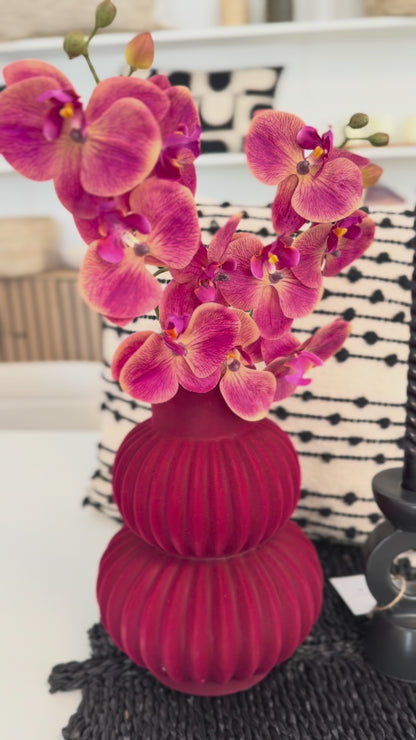 Video die zeigt rote bauchige vase mit Rote Orhudeen,neben hat schwarze Krzenständer und hunten ein schwarz-weiss Kissen.Video zeigt diese arangiment aus verschiedene winkeln