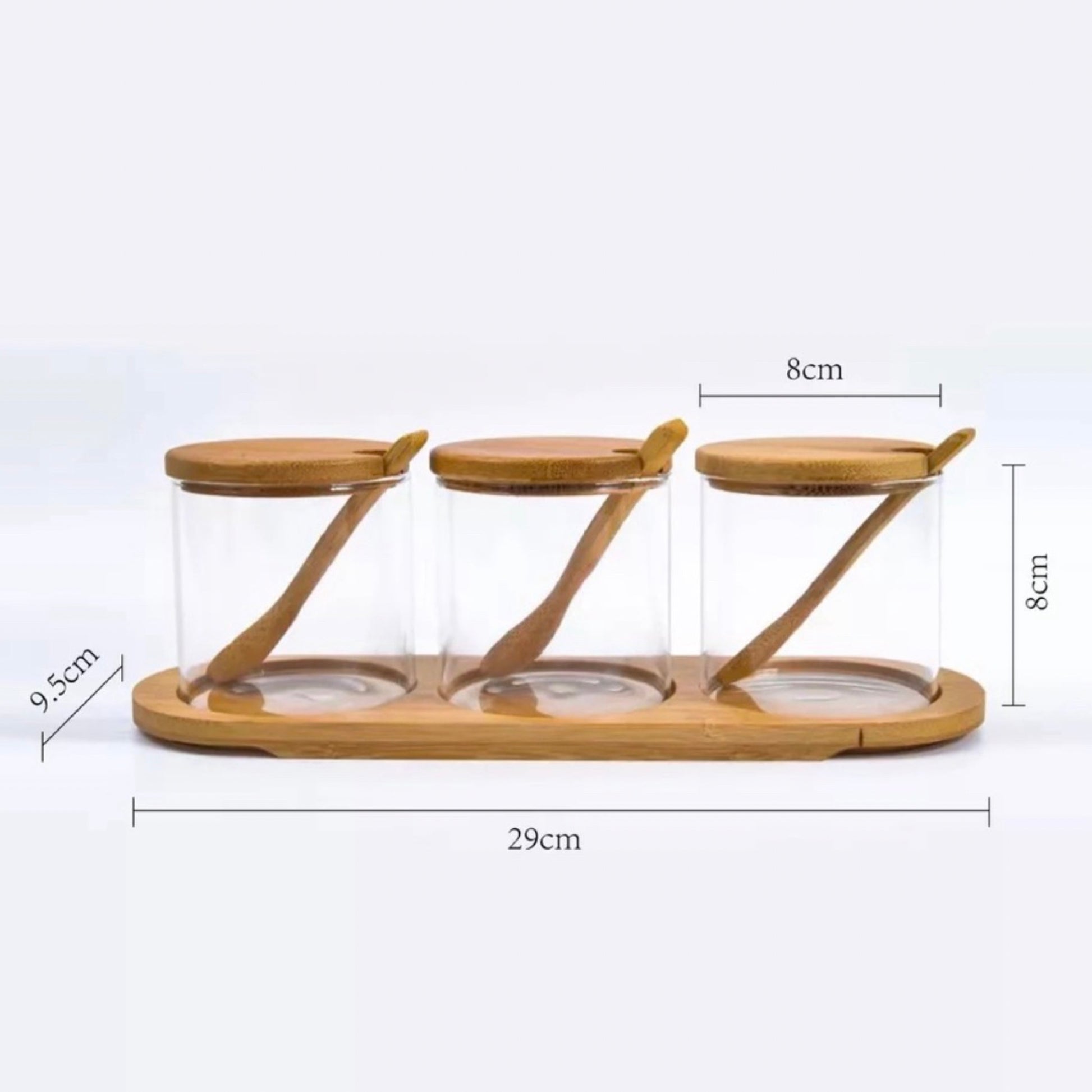 Drei leere, klare Gewürzgläser mit Bambusdeckeln auf einem passenden Bambustablett, das die Gläser elegant präsentiert. Jedes Glas ist mit einem Bambuslöffel ausgestattet, der schräg über den Öffnungen liegt. Die Maße sind klar angegeben: jedes Glas misst 8 cm in der Höhe und Breite, während das Tablett eine Länge von 29 cm und eine Breite von 9,5 cm aufweist.